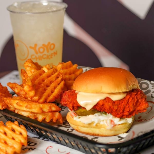 Yoyo Chicken's spicy fried chicken sandwich with waffle fries and a drink.