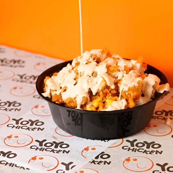 Yoyo Chicken's fried chicken and corn bowl, drizzled with white sauce, on branded paper.