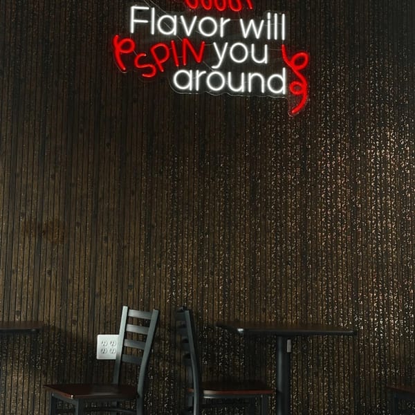 Yoyo Chicken's neon sign on a dark wooden wall, with tables and chairs below.