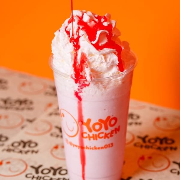 Yoyo Chicken milkshake with whipped cream and red syrup on a branded paper background.