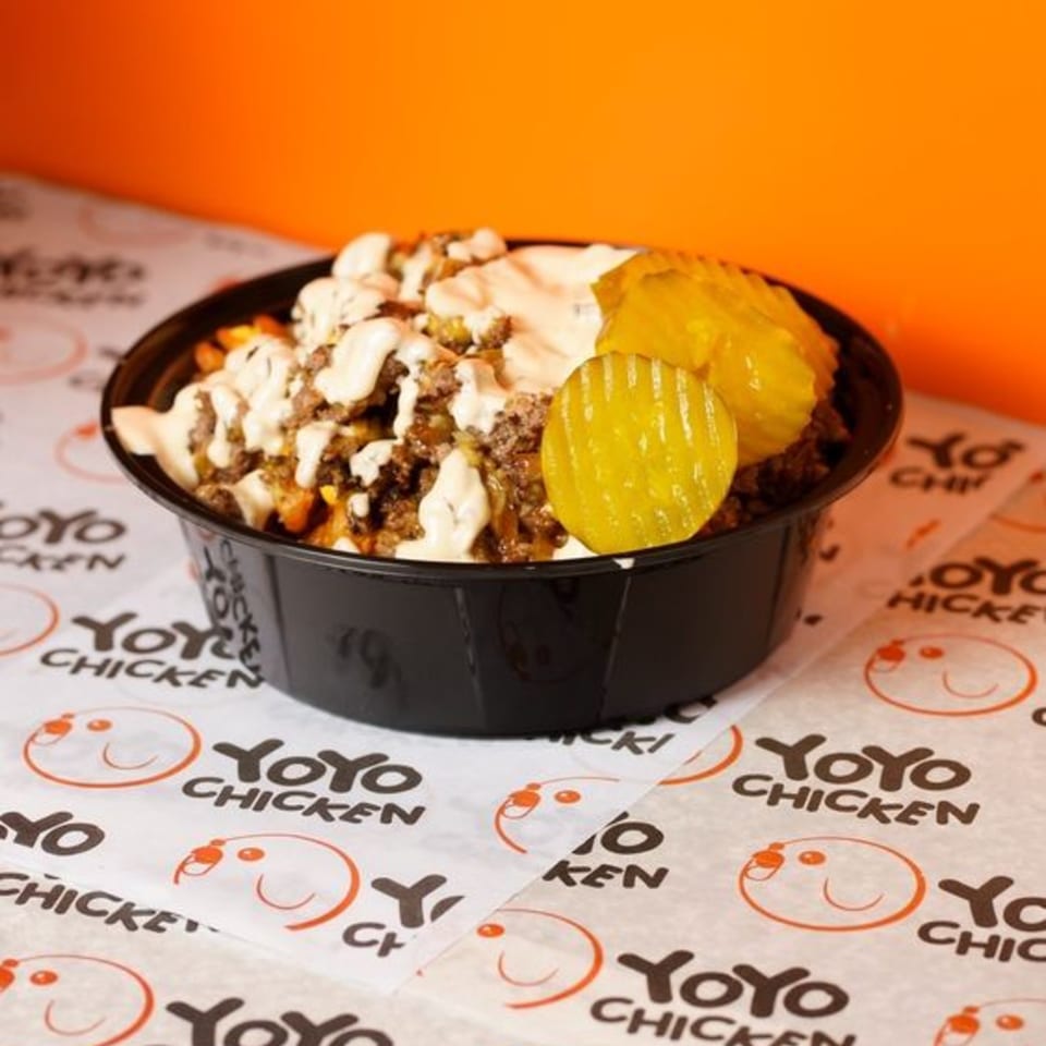 Yoyo Chicken's loaded fries with ground meat, white sauce, and pickles in a black bowl.