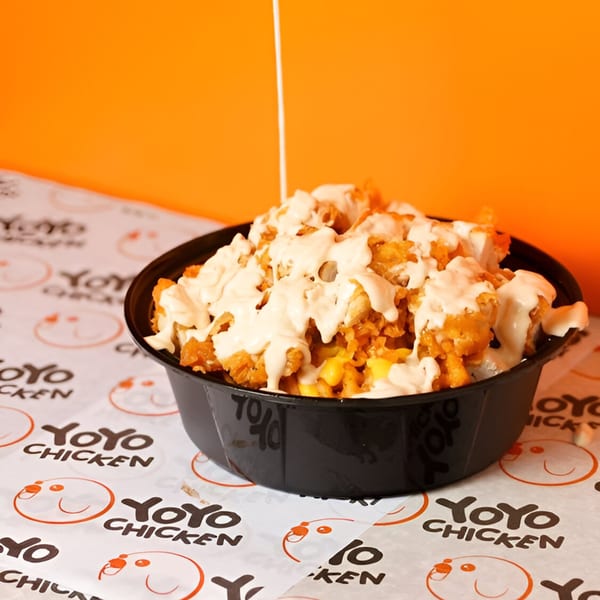 Yoyo Chicken's fried chicken and corn bowl, drizzled with creamy sauce, on branded paper.