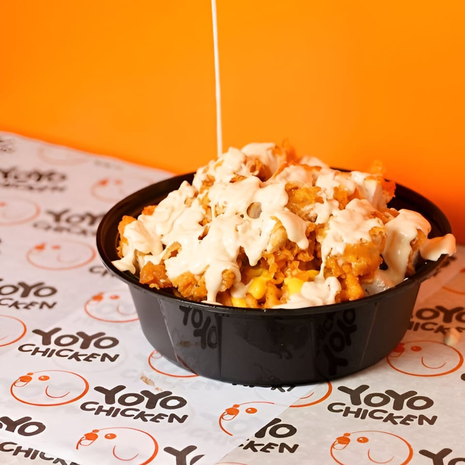 Yoyo Chicken's fried chicken and corn bowl, drizzled with creamy sauce, on branded paper.