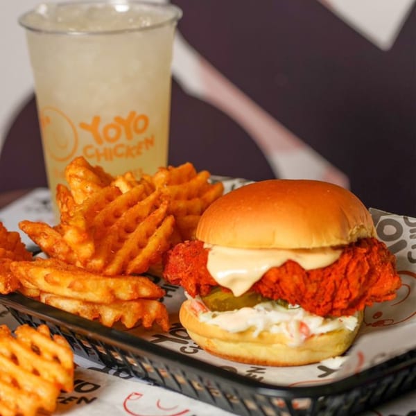 Yoyo Chicken's spicy fried chicken sandwich with coleslaw, pickles, waffle fries, and a drink.