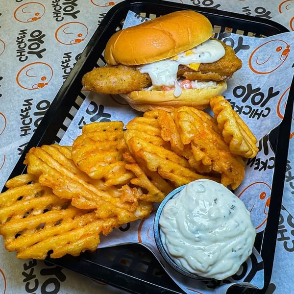 Yoyo Chicken's fried chicken sandwich with waffle fries and a side of dipping sauce.