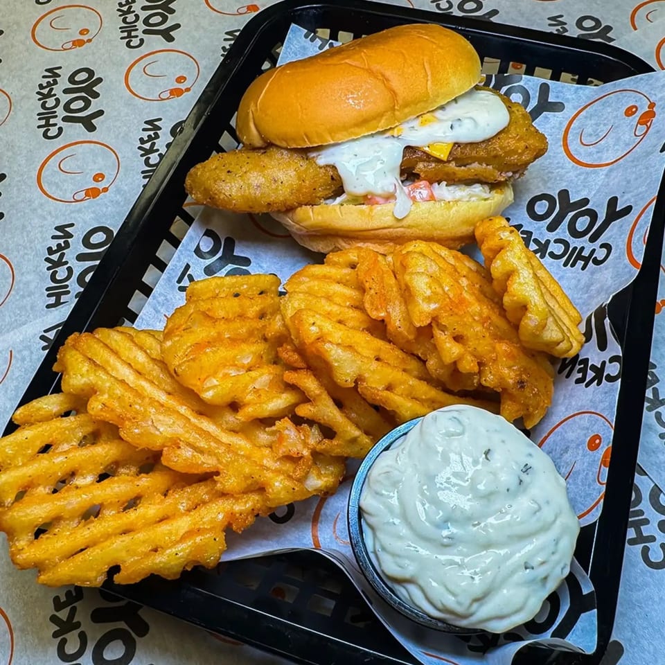Yoyo Chicken's fried chicken sandwich with waffle fries and a side of dipping sauce.