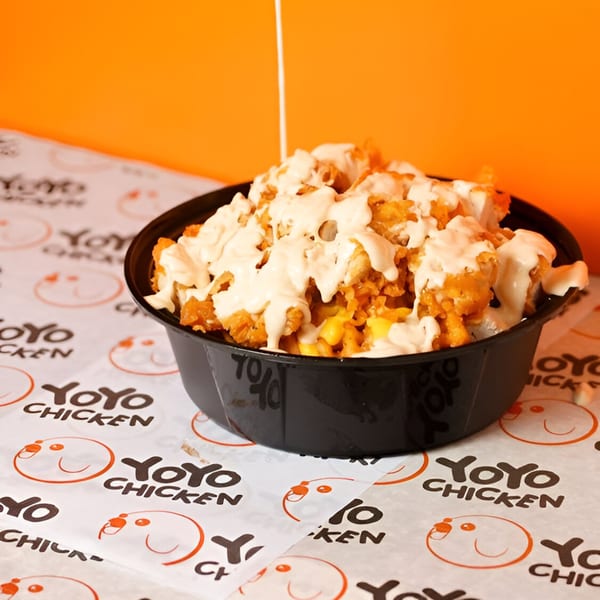 Yoyo Chicken's fried chicken and corn bowl, drizzled with creamy sauce, on branded paper.