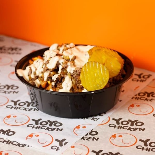 Yoyo Chicken's loaded fries with ground meat, white sauce, and pickles in a black bowl.