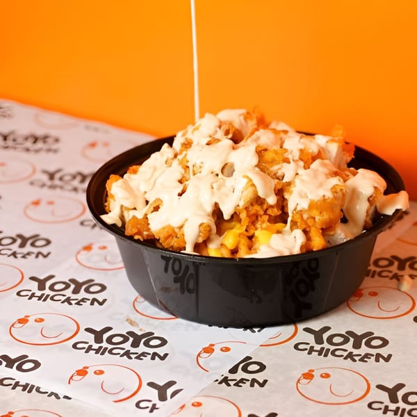 Yoyo Chicken's fried chicken bites with sauce and corn, served in a black bowl on branded paper.