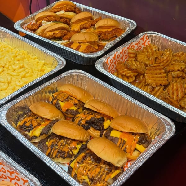 Catering trays of Yoyo Chicken fried chicken sliders, cheeseburger sliders, mac and cheese, and waffle fries.