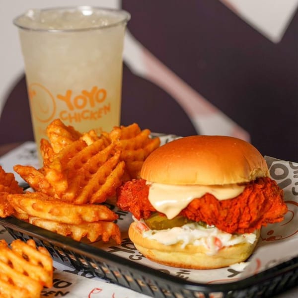 Yoyo Chicken's spicy fried chicken sandwich with coleslaw, pickles, waffle fries, and a drink.